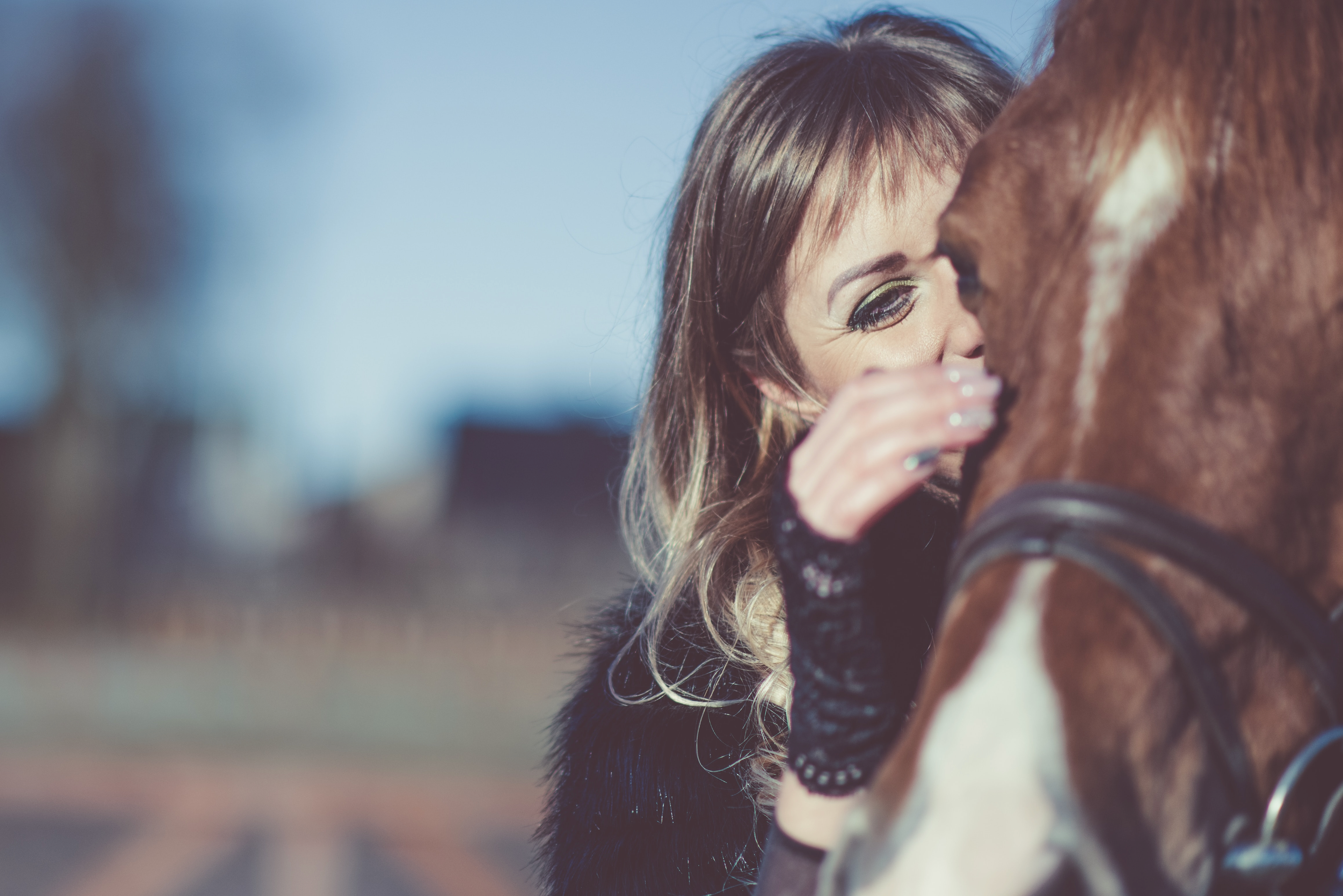 Woman gazing into the eyes of a brown and white horse