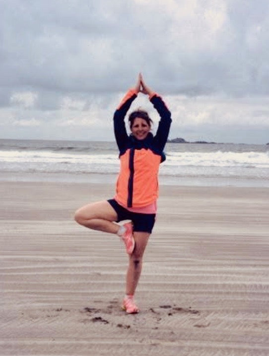 Person practicing yoga on a beach with ocean and sky in the background